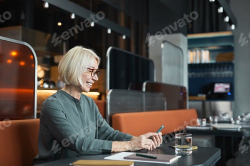 Preview: Smiling Woman Using Mobile Phone in Modern Restaurant