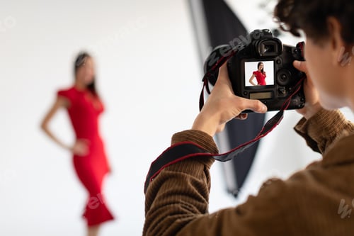 Preview: Professional male photographer and beautiful female model in red dress making beauty or content