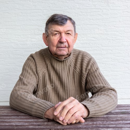 Senior Man Sitting Calmly at Wooden Table