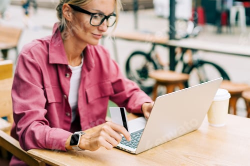 Preview: Young woman working on laptop in cafe