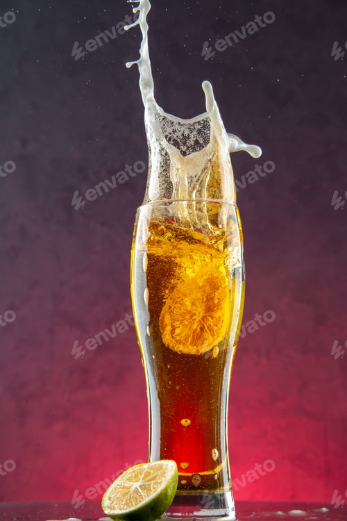 Preview: Side view of delicious pure beer in a glass with foam and lemon slice on purple background