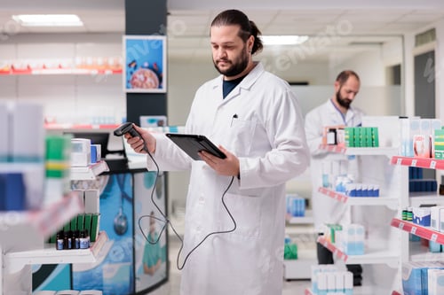 Preview: Pharmacist in white coat looking at pills packages while scanning pharmaceutical products using
