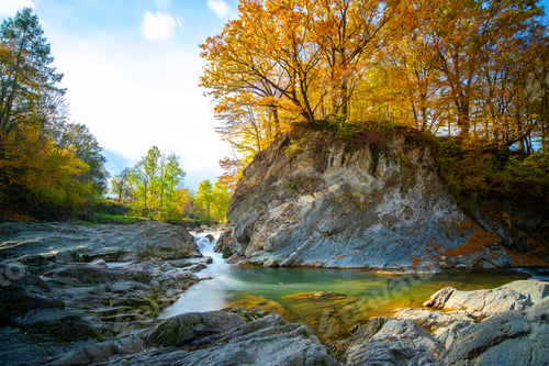 Preview: Mountain river with small waterfall with clear turquoise water falling down between wet boulders