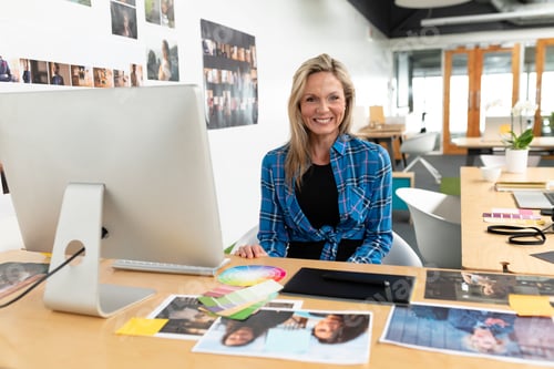 Preview: Working woman arranging photos and color swatches on desk in studio, with graphics tablet