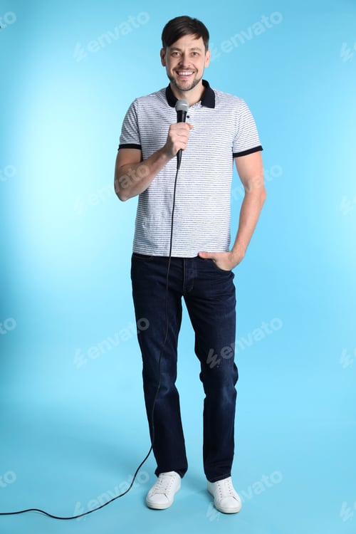 Preview: Handsome man in casual clothes posing with microphone on color background