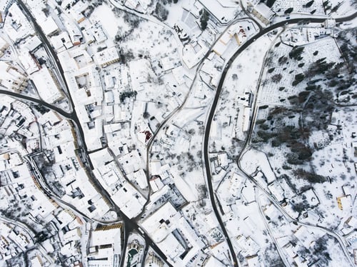 Preview: Aerial view of small town with hills in winter.