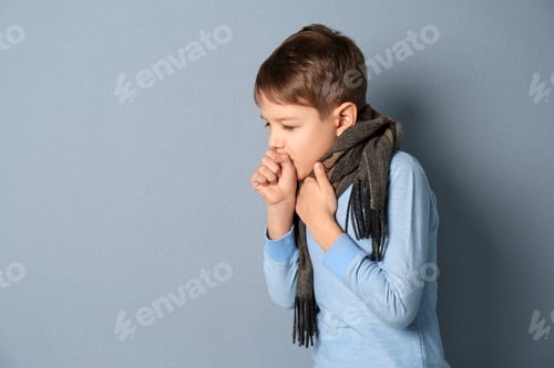 Preview: Little boy coughing on grey background