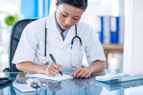 Preview: Concentrated doctor writing on notebook in medical office