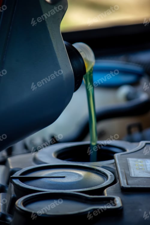 Preview: An auto mechanic changing oil pours oil into a car engine.