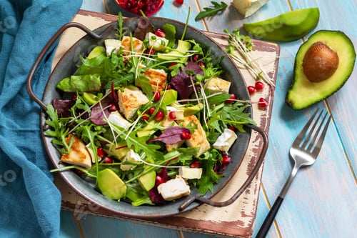 Preview: Summer arugula salad with chicken, avocado, pomegranate and cheese on wooden table. Top view.