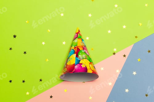 Preview: Festive party hat on colored background with shiny stars and confetti decorations