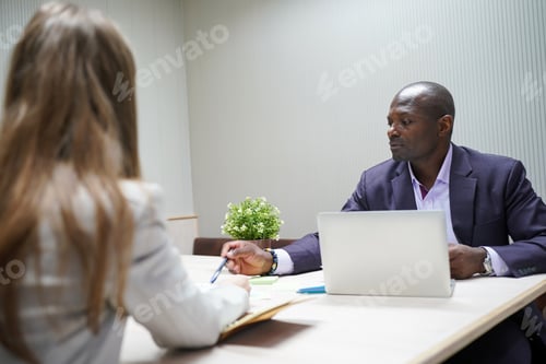 Preview: Image of young businessmen and colleague discussing document in laptop and touchpad at meeting