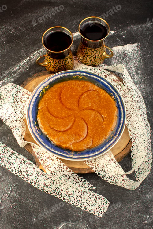 Preview: a top view sweet delicious halva yummy eastern sweet dessert inside plate with tea on the dark