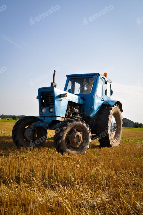 Preview: Closeup of a blue tractor parked in an open field