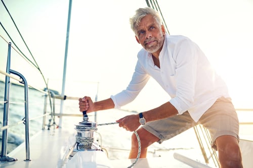 Preview: Mature man using a winch while out sailing