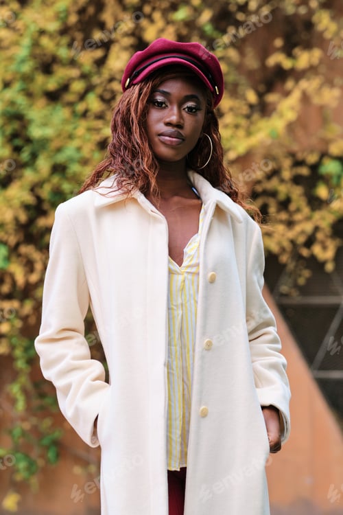 Preview: Stylish woman looking at camera while posing outdoors.
