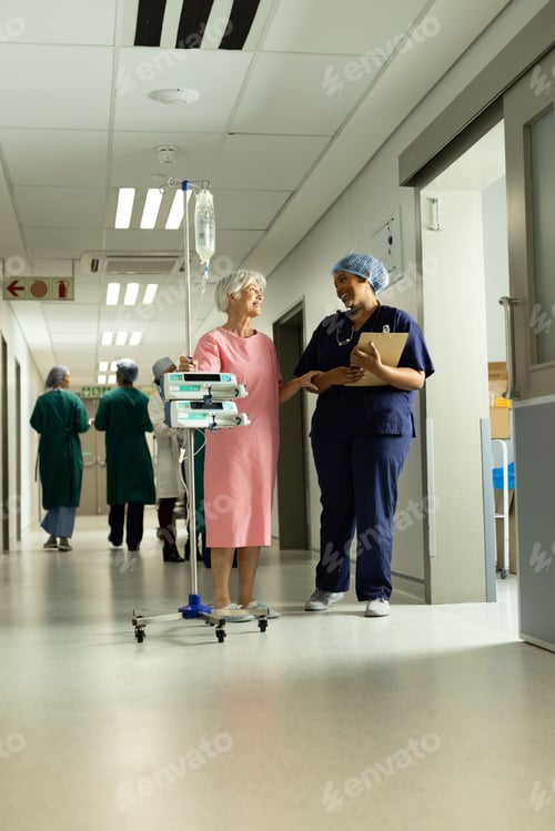 Preview: Diverse female doctor and caucasian senior female patient with iv pole talking
