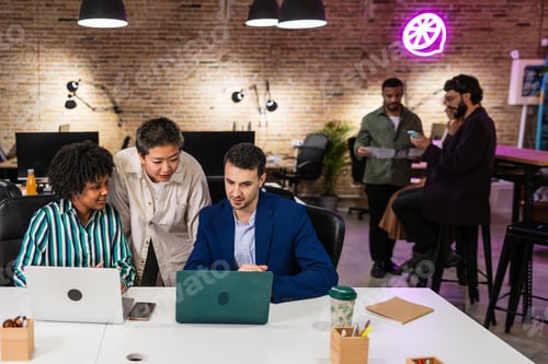 Preview: Multi ethnic team collaborating on laptops in modern office