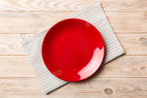 Preview: Top view on colored background empty round red plate on tablecloth for food. Empty dish