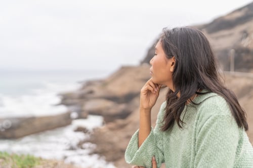Preview: Serene latin woman looking at the ocean from viewpoint