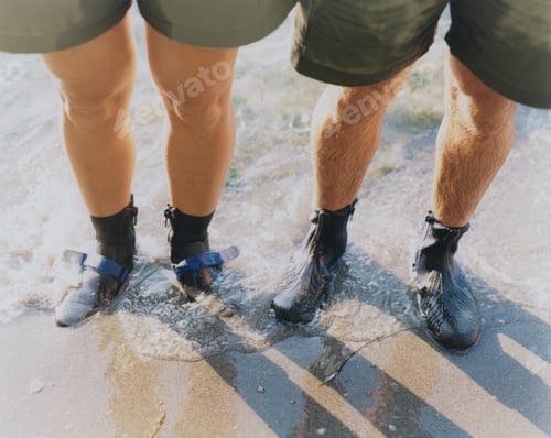 Preview: Man and woman wearing waterproof booties, standing in surf