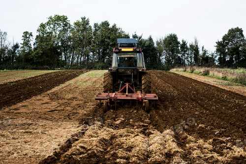 Preview: Rear view of tractor plowing a field on a farm.