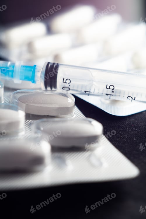 Preview: Vertical shot of pharmaceutical capsules, pills and syringes