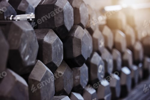 Preview: Closeup of stacked and piled heavy dumbbell weights arranged in empty gym with nobody during day. W