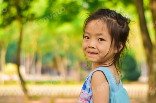 Preview: Close-up portrait of smiling beautiful little girl in a summer green park.