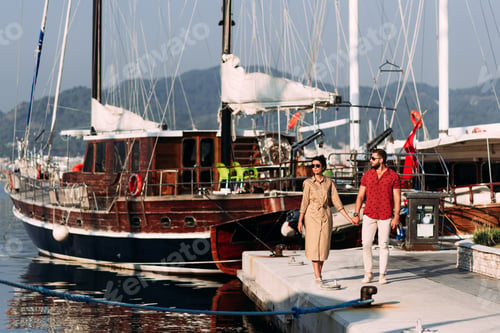 Preview: Man and woman near the yachts on the dock. Couple in love at the yacht