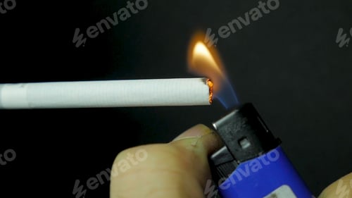 Preview: Hand lighting lighter cigarette closeup. Burning cigarette on black background. Cigarette closeup on