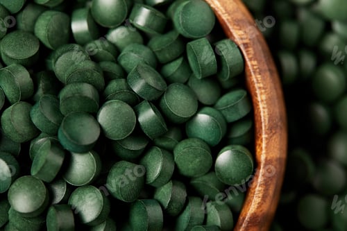 Preview: close up view of wooden bowl with pile of spirulina pills