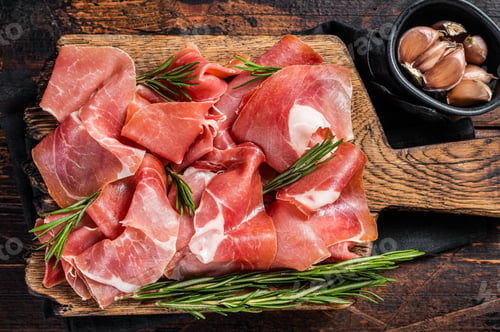 Preview: Slices of jamon serrano ham or prosciutto crudo parma on wooden board with rosemary