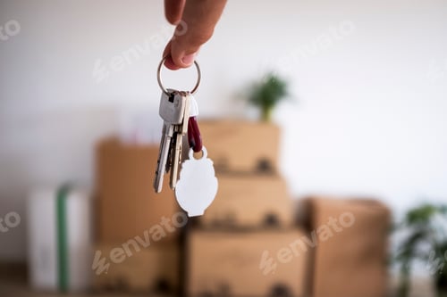 Preview: Close-up of the keys of the new empty apartment with moving boxes on the floor