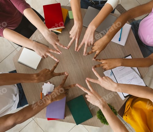 Preview: Multiracial students joining victory signs in circle, top view