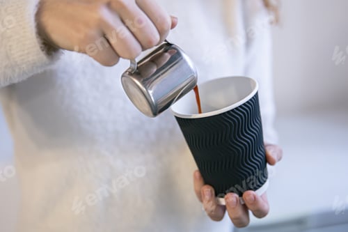 Preview: Close-up of female hands of baristas pouring espresso into a glass.