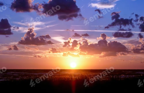 Preview: Vibrant sunset illuminating clouds over a tranquil landscape