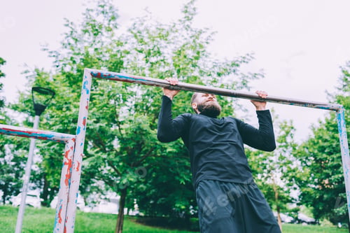 Preview: Young handsome caucasian bearded sportsman doing pull-up