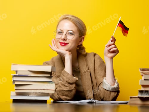 Preview: Style blonde woman sitting at table with books and flag of Germany on yellow background