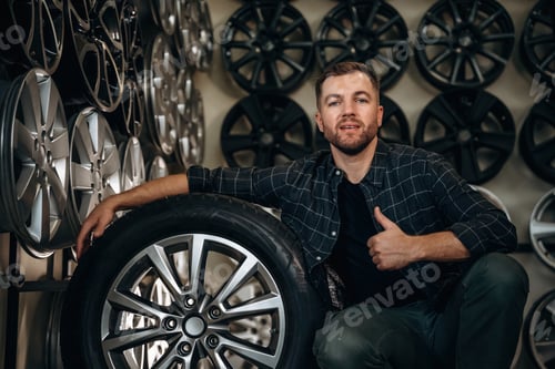 Preview: Thumb up, gesture. Man worker is maintenance station with tires, wheels