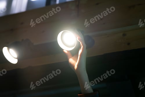 Preview: A man reaches up to replace a light bulb in the ceiling