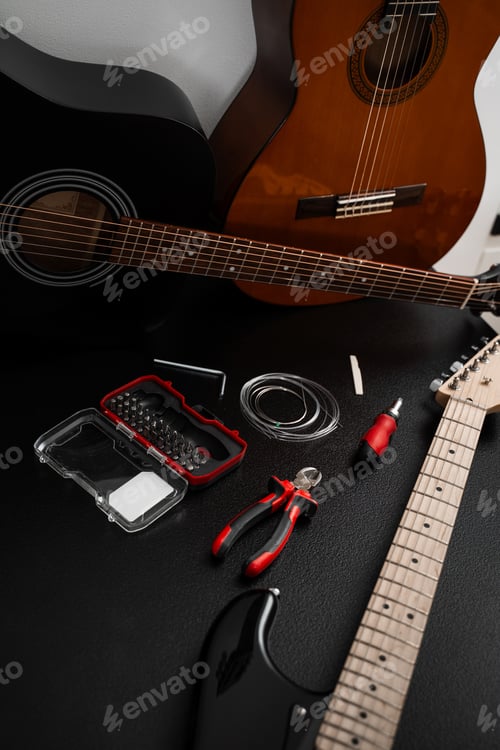 Preview: Electric and acoustic guitars surrounded by repair tools, wire cutters, and spare strings