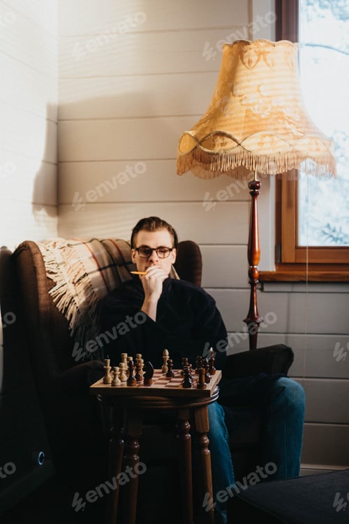 Preview: Man in Armchair Contemplates Chess Game Strategy