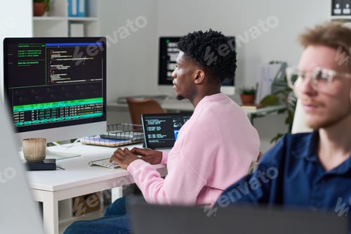 Preview: Young Black Man Debugging Software Code on Desktop Computer in Office