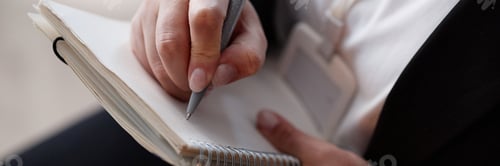 Preview: Header Image of Woman Writing in Notebook at Business Meeting Indoors
