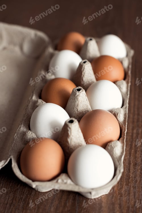 Preview: Top view natural and organic chicken eggs brown and white in craft box on wooden table
