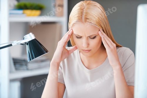Woman Suffering from Headache at Desk Indoors