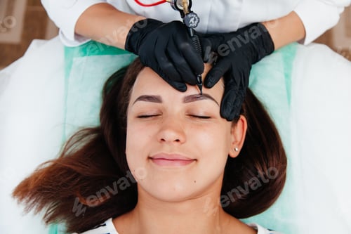 Preview: Permanent tattoo brow makeup, beauty studio master making beautiful brows on female face.