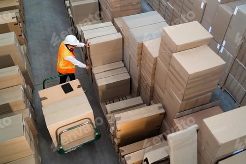 Preview: Logistic warehouse worker delivering boxes on a trolley