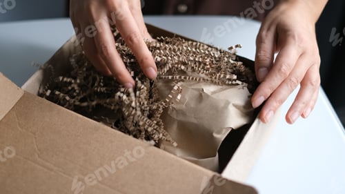 Preview: woman opening parcel indoors. woman opening and unpacking cardboard box parcel